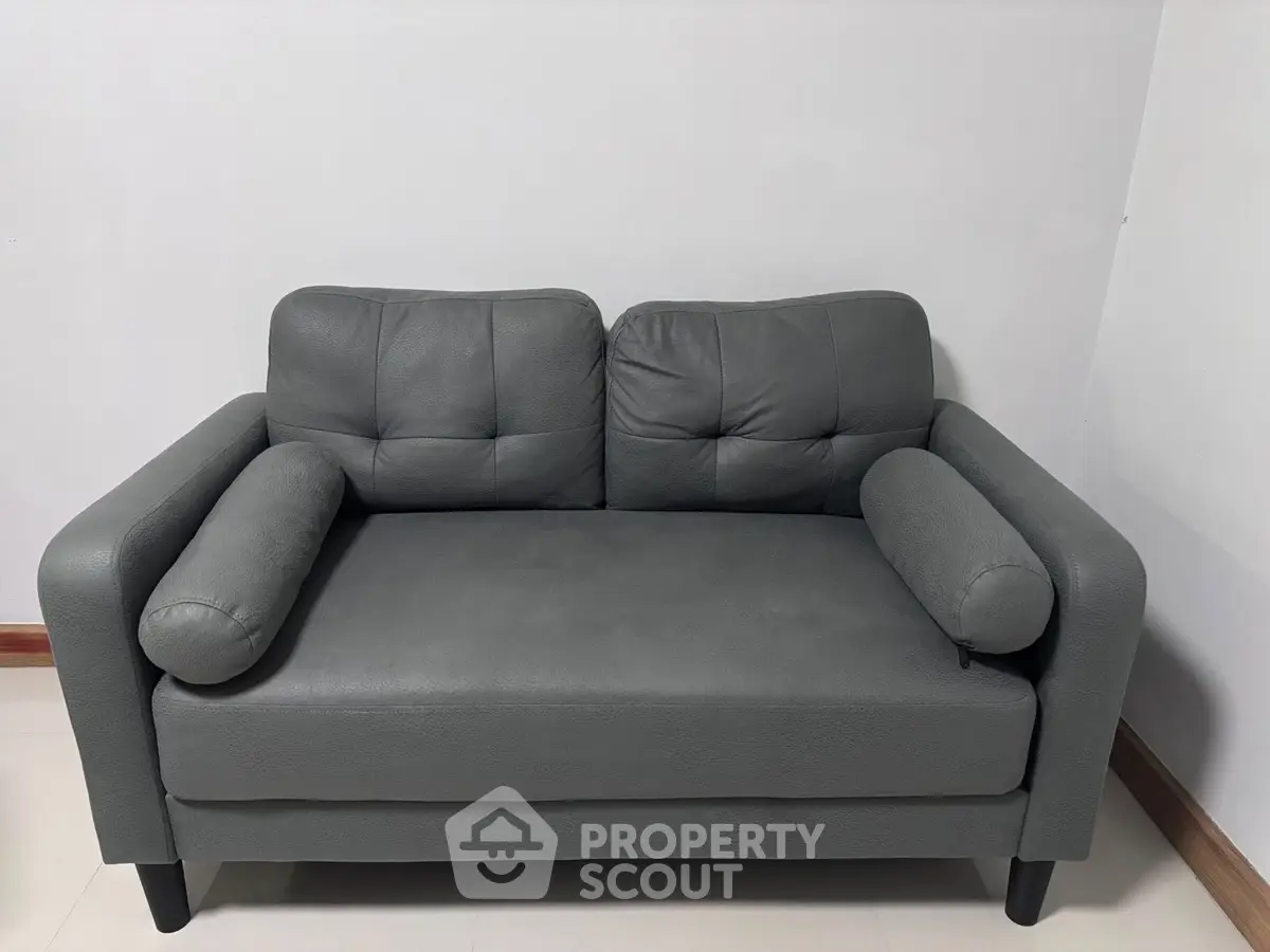 Modern gray sofa in minimalist living room setting.