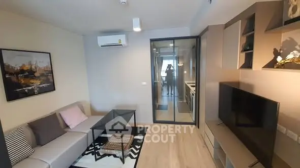 Modern living room with stylish decor and glass partition leading to kitchen.