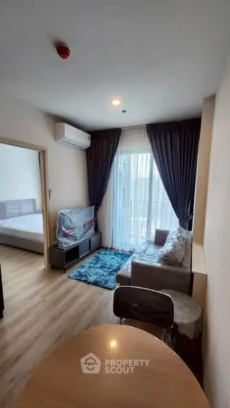 Modern living room with natural light and cozy furnishings in a stylish apartment.