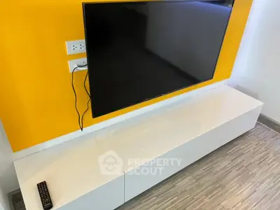 Modern living room with sleek TV setup and vibrant yellow accent wall.