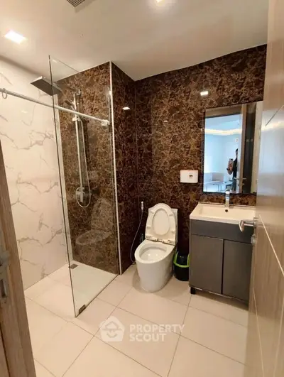 Luxurious bathroom with modern shower and elegant marble walls in upscale property.
