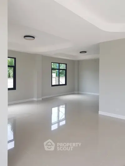 Spacious and bright living room with large windows and modern lighting, perfect for family gatherings.