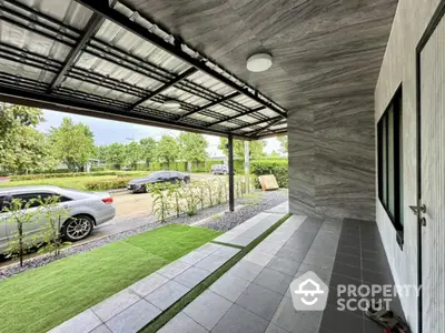 Modern covered entrance with sleek design and lush greenery