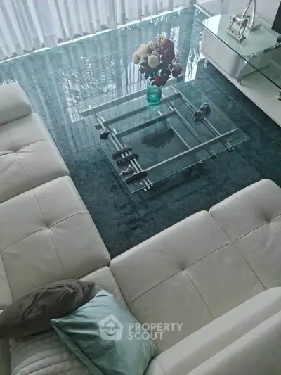 Luxurious modern living room with elegant glass coffee table and plush white sectional sofa.