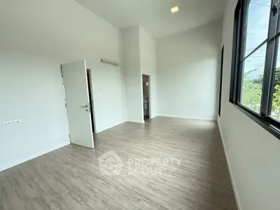 Spacious empty room with large windows and wooden flooring, perfect for customization.