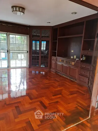 Spacious living room with polished wooden floors and built-in shelving.
