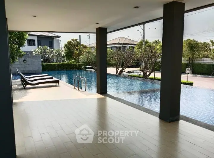 Luxurious poolside view with modern architecture and lush greenery, perfect for relaxation and leisure.