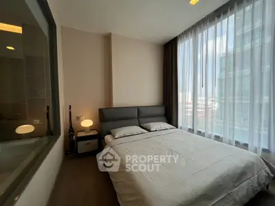 Modern bedroom with large windows and city view, featuring a cozy bed and stylish decor.