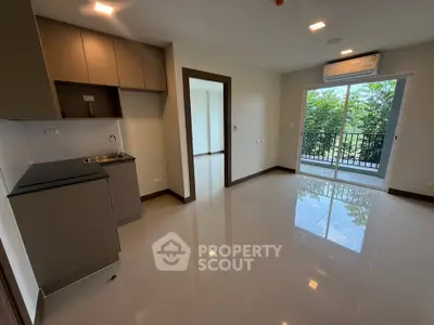 Modern open-layout kitchen and living area with balcony view in a bright apartment.