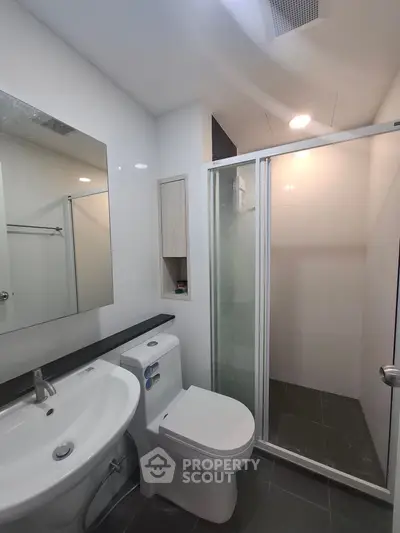Modern bathroom with sleek fixtures and glass shower enclosure in a contemporary apartment.