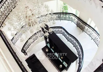 Luxurious grand staircase with elegant chandelier and ornate railing in a high-end property.