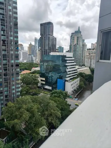 Stunning cityscape view from a high-rise balcony showcasing modern architecture and lush greenery.