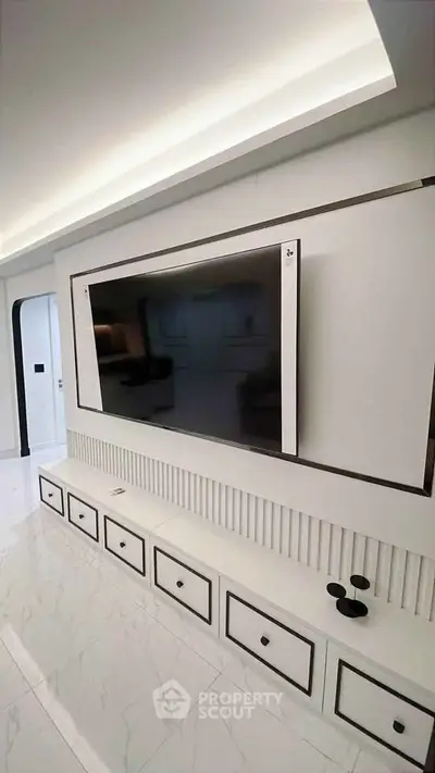 Modern living room with sleek TV setup and elegant white cabinetry