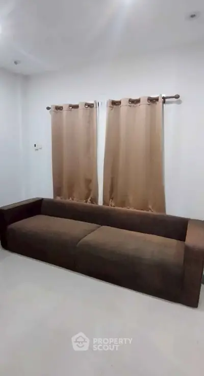 Spacious living room with modern brown sofa and elegant curtains, perfect for relaxation and entertaining guests.
