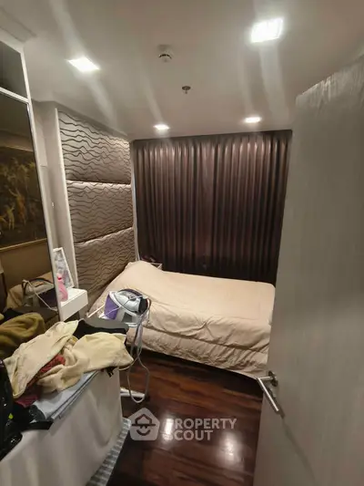 Cozy bedroom with modern decor and wooden flooring, featuring a comfortable bed and stylish curtains.