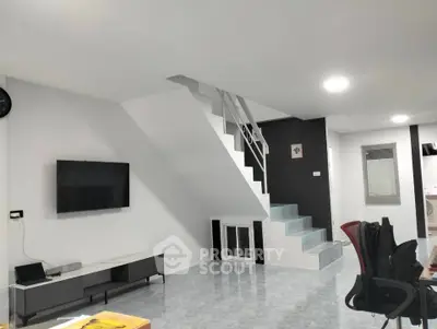 Modern living room with sleek staircase and wall-mounted TV, perfect for contemporary living.