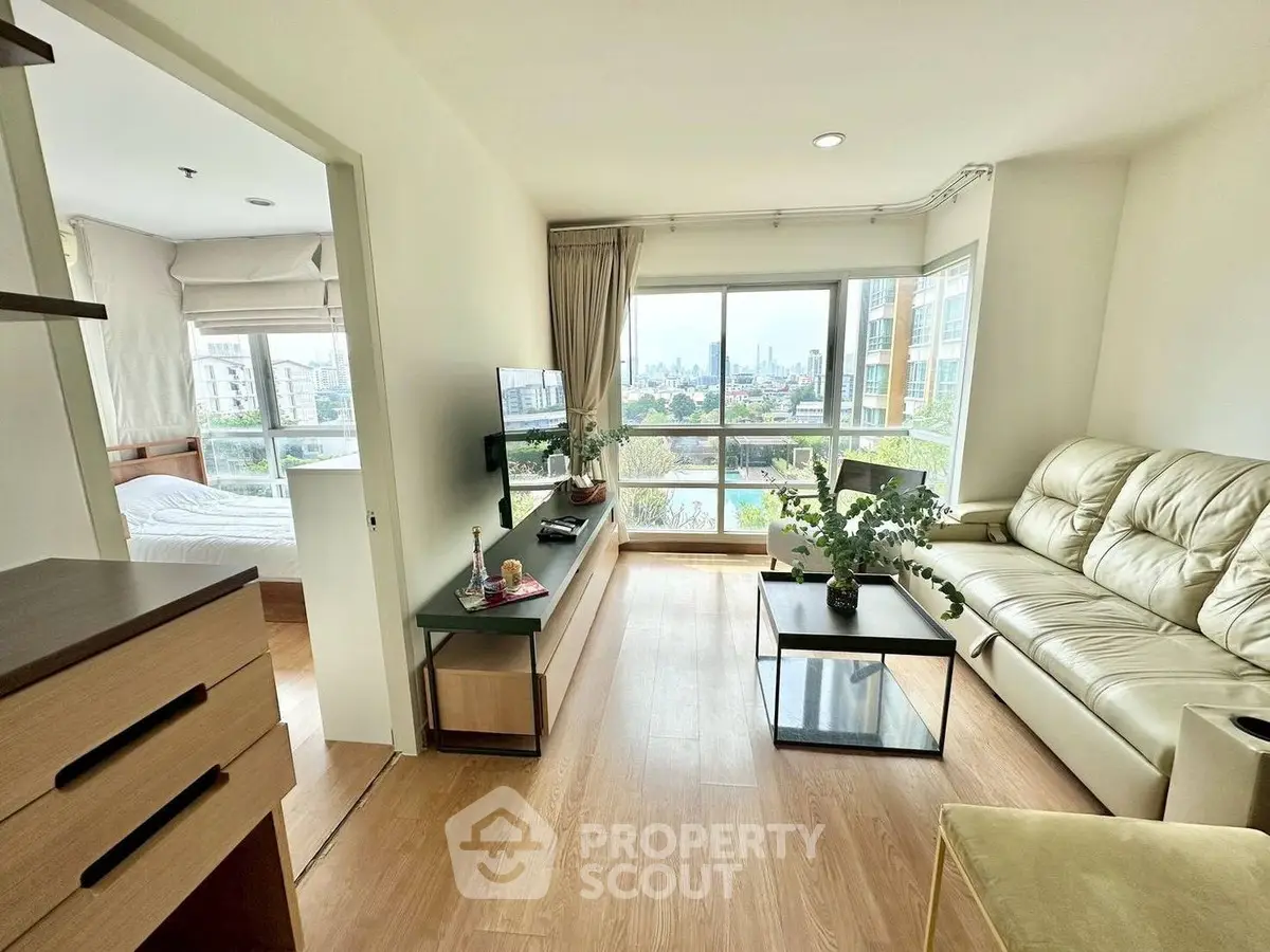 Modern living room with natural light and city view, featuring cozy seating and stylish decor.