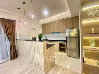 Modern kitchen with open layout, stylish pendant lights, and stainless steel appliances in a cozy apartment.