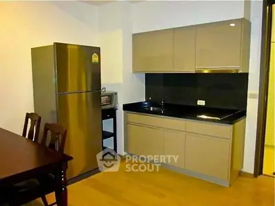 Modern kitchen with sleek cabinets and stainless steel fridge in a cozy apartment.