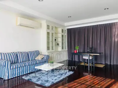 Spacious living room with stylish decor and natural light, featuring a cozy sofa and elegant workspace.