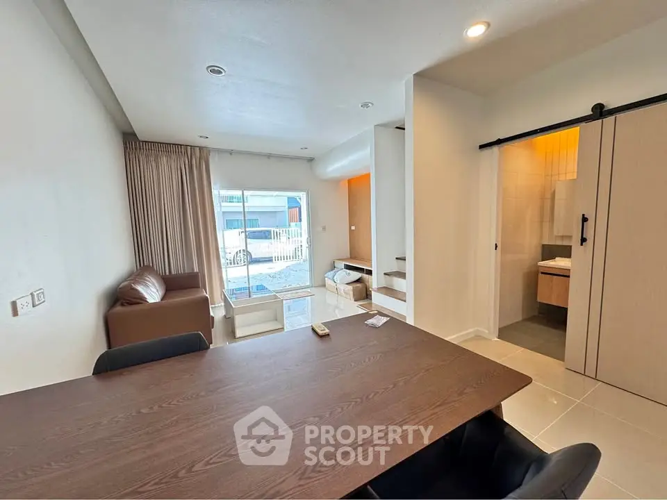 Modern open-plan living room with dining area and sliding bathroom door