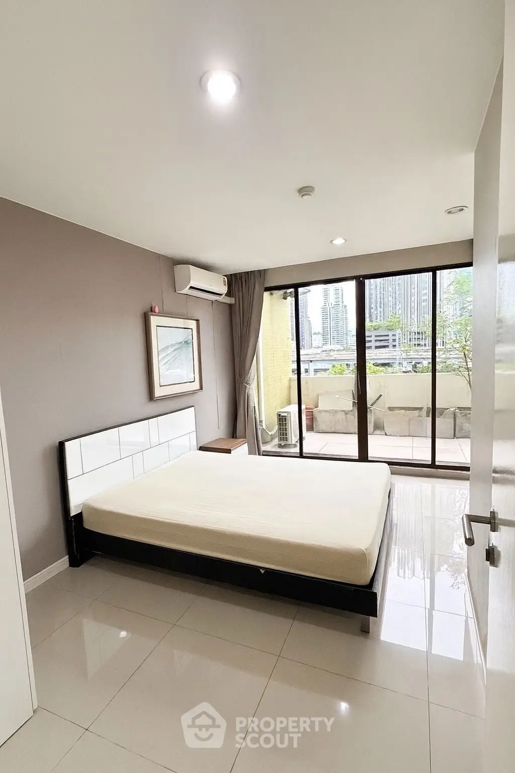 Spacious bedroom with balcony access and city view in modern apartment