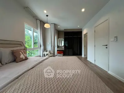Spacious bedroom with modern decor and large window overlooking greenery