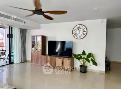 Spacious living room with modern decor, large TV, and balcony access, perfect for relaxation and entertainment.