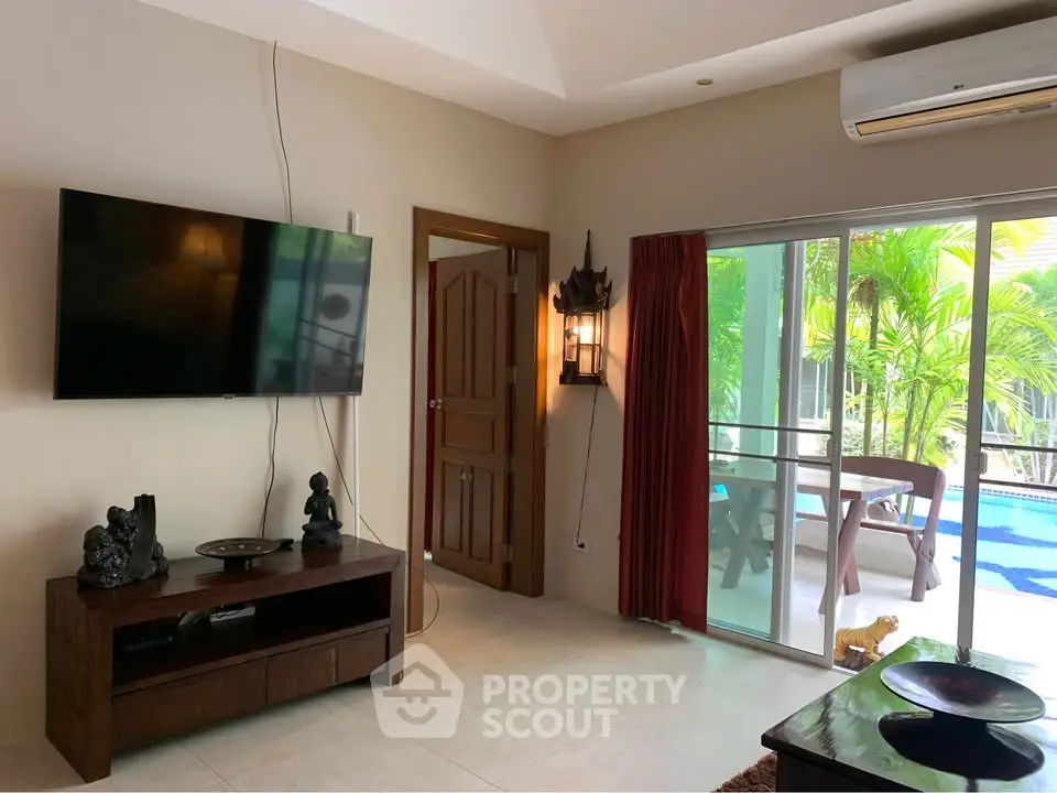 Spacious living room with pool view, modern decor, and large TV, perfect for relaxation and entertainment.