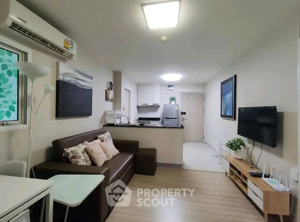 Modern living room with open kitchen, featuring sleek furniture and contemporary decor.