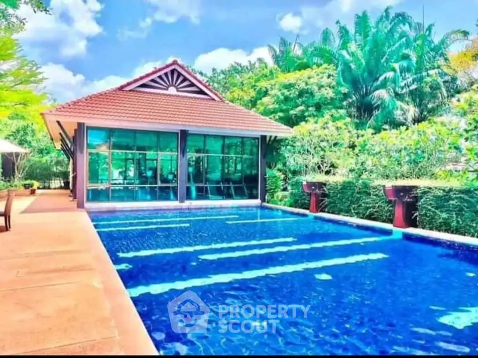 Luxurious poolside view with modern clubhouse surrounded by lush greenery