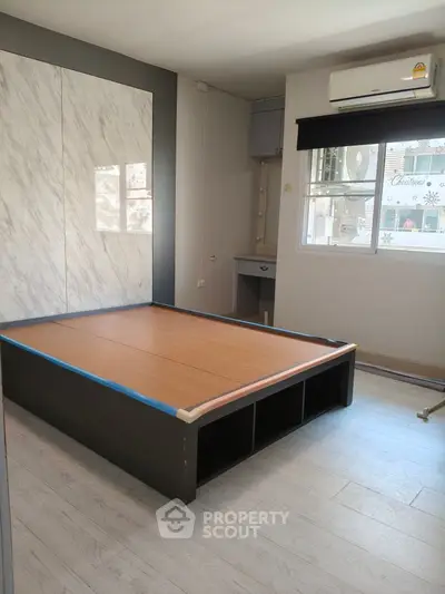 Modern bedroom with built-in storage and air conditioning, featuring sleek design and natural light.