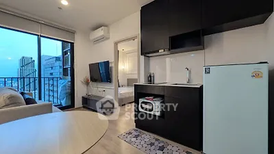 Modern apartment with open kitchen and living area, featuring sleek black cabinetry and a city view balcony.