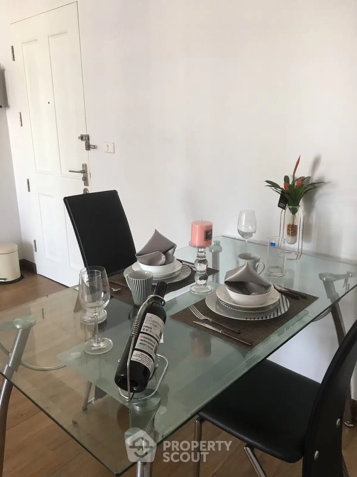 Modern dining area with glass table and elegant place settings in a stylish apartment.