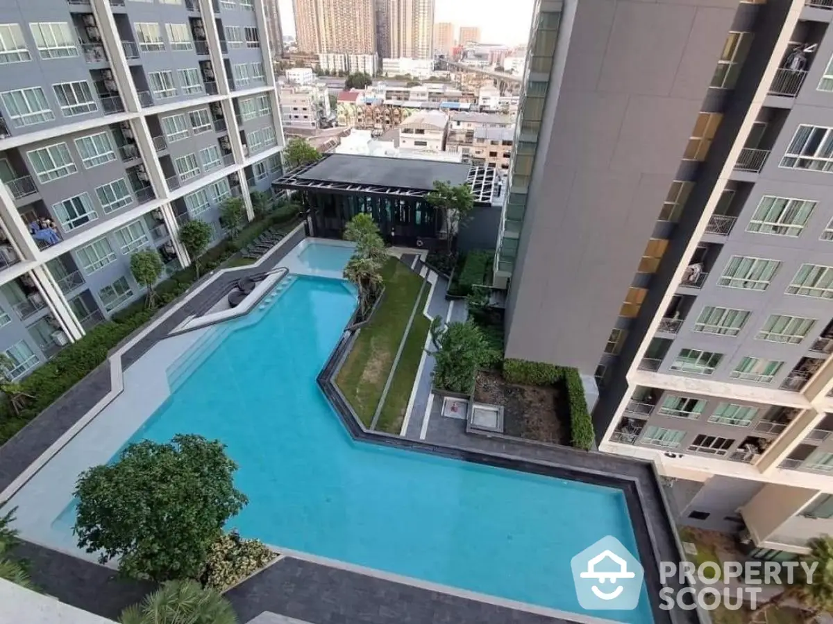 Stunning aerial view of modern condominium with luxurious swimming pool and lush greenery.