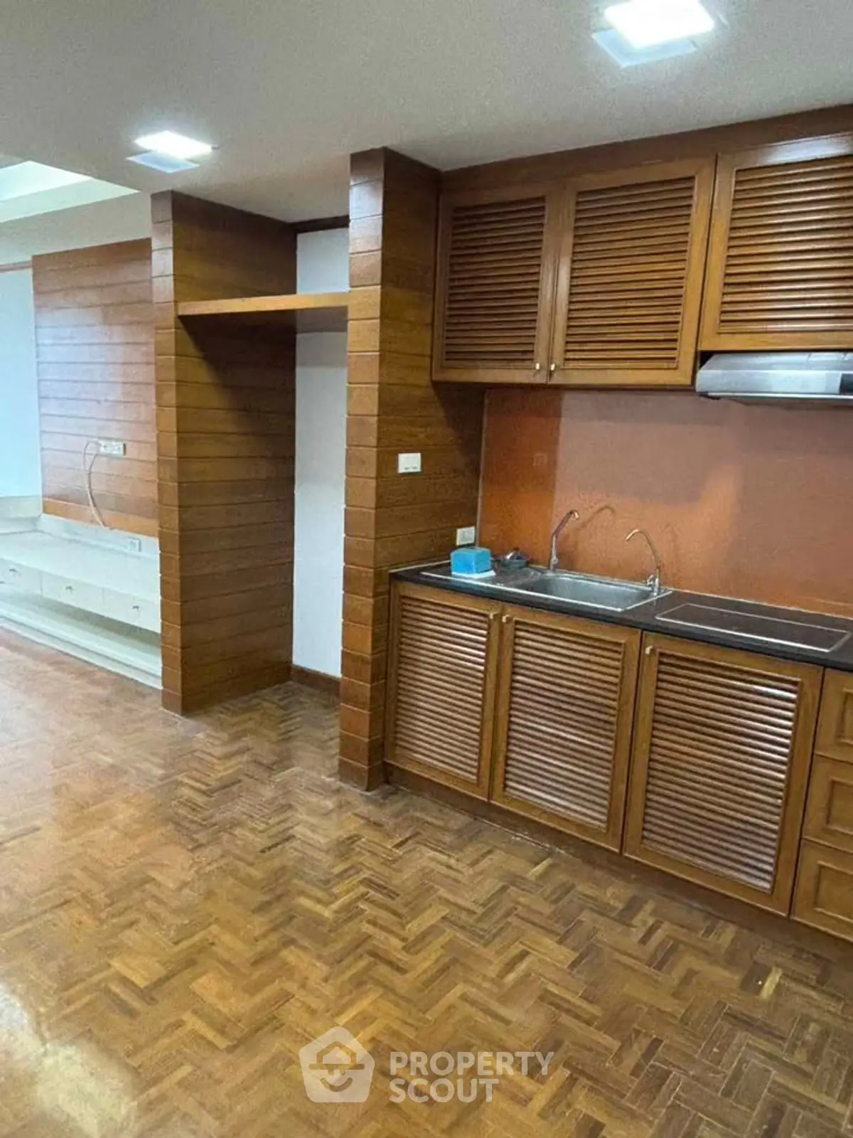 Charming kitchen with wooden cabinetry and parquet flooring, perfect for cozy home cooking.