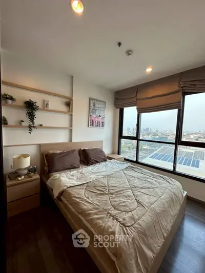 Modern bedroom with large window offering stunning city view, cozy decor, and elegant shelving.