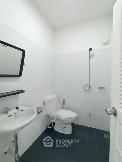 Modern minimalist bathroom with white tiles and sleek fixtures.
