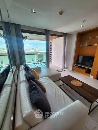 Modern living room with large windows and balcony access, featuring stylish furniture and a cozy ambiance.