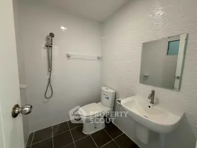 Modern bathroom with sleek fixtures and minimalist design, featuring a shower, toilet, and sink.