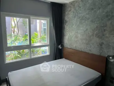 Cozy bedroom with large window and modern decor, offering a serene garden view.