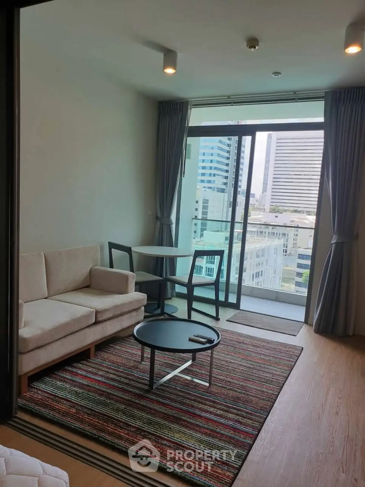 Modern living room with city view, featuring cozy sofa and stylish decor.