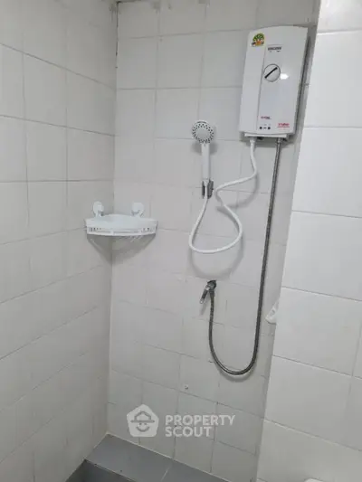 Compact bathroom with electric shower and tiled walls, ideal for modern living spaces.