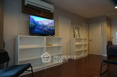 Spacious living room with modern TV and sleek white shelves