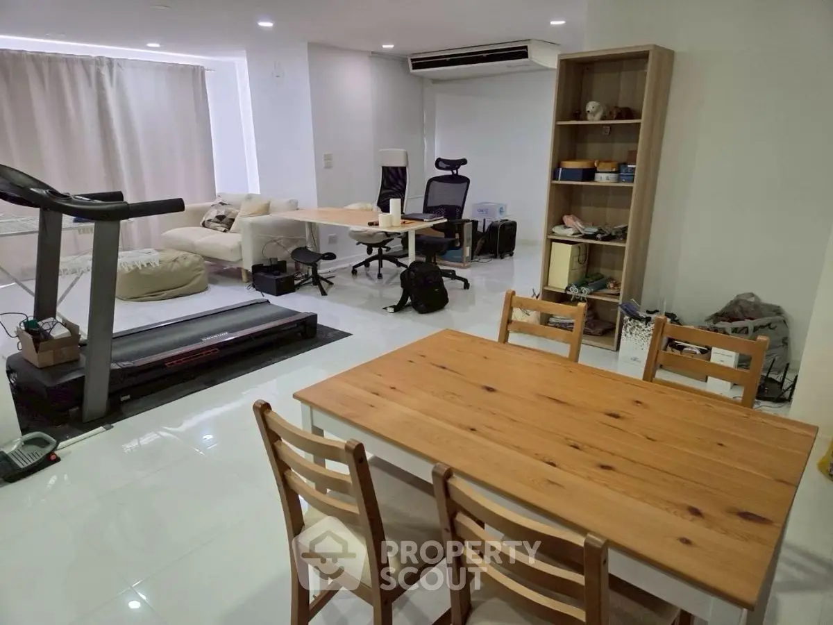 Spacious open-plan living and dining area with modern furniture and treadmill.
