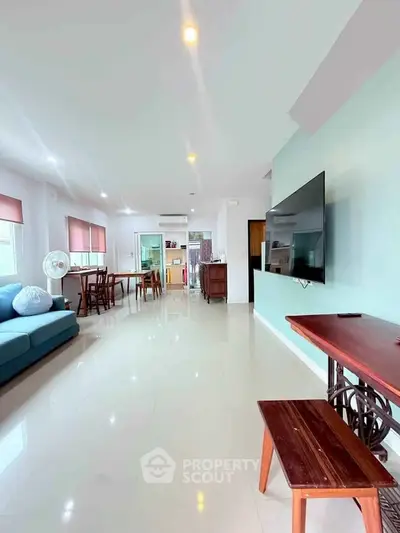 Spacious living room with modern decor and large TV, perfect for family gatherings.
