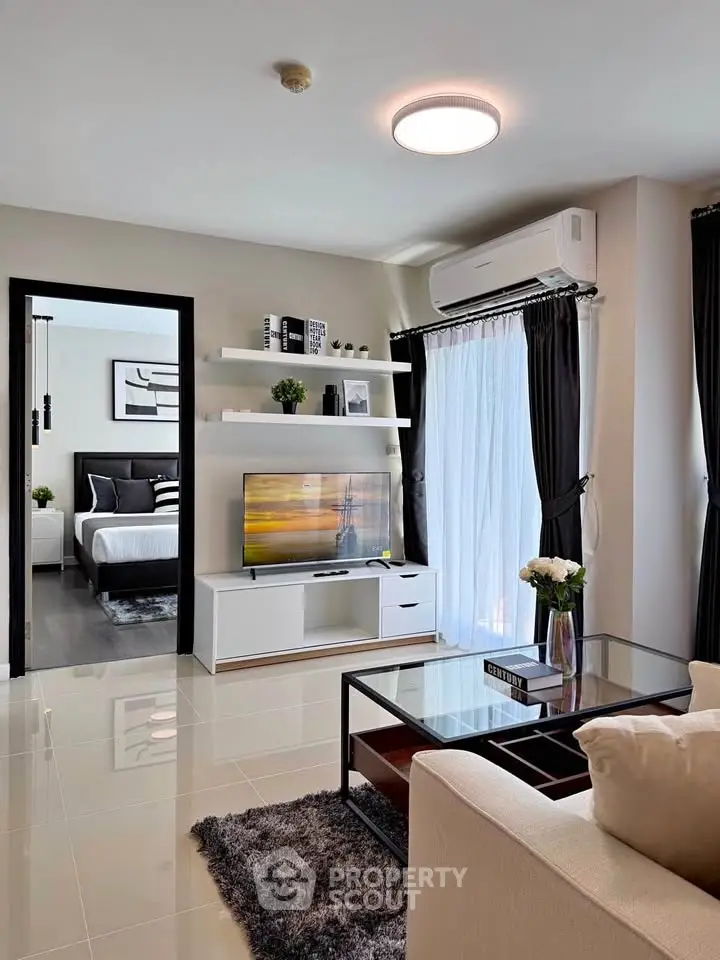 Modern living room with sleek design, large windows, and a view into a stylish bedroom.