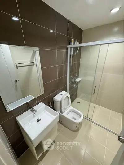 Modern bathroom with glass shower and sleek fixtures in contemporary apartment.