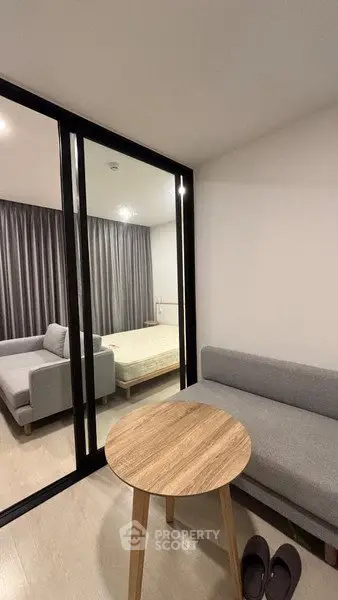 Modern apartment with cozy living area and bedroom separated by glass partition.