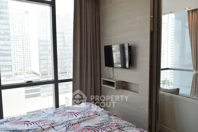 Modern bedroom with city view, featuring a wall-mounted TV and large windows for natural light.